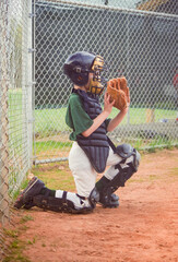 Young boy reluctantly playing the position of a baseball catcher