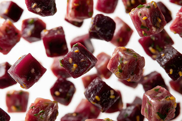 Colorful cubes of fresh beetroot and herbs are suspended in mid-air, showcasing vibrant textures and rich colors, ideal for culinary presentations and food photography