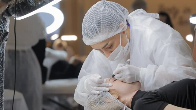Beautician performing microblading procedure on client's eyebrows, sterile environment with close attention