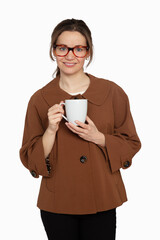 Femme avec lunettes, manteau brun et tasse de caf&eacute; souriante