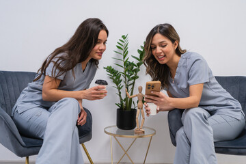 Physiotherapists enjoy a break, sharing a moment with coffee and a smartphone