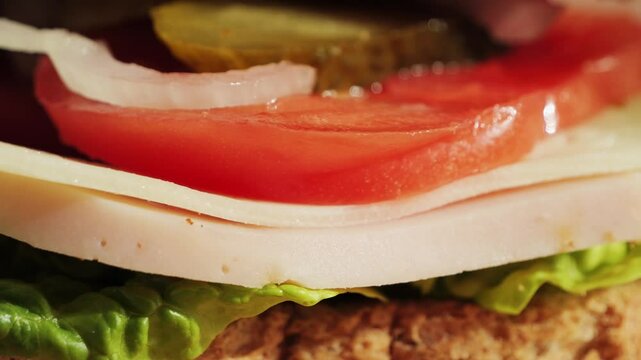 Close up of a homemade sandwich, toasted bread with ham juicy tomato, pickled cucumber, onion and lettuce. High quality 4k footage