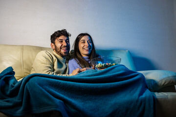 Happy couple watching tv and eating popcorn on sofa at night © Ivi - Powerlightss