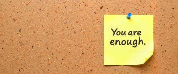 Motivational sticky note with message "You are enough" on wall - copy space  