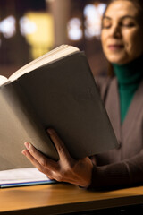 Ambitious woman reading specialty books in a campus library, writing notes for her master degree...