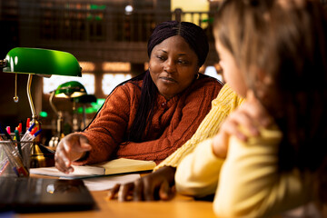 Elementary school professor engaging with girls students during private lessons, provides tutoring...