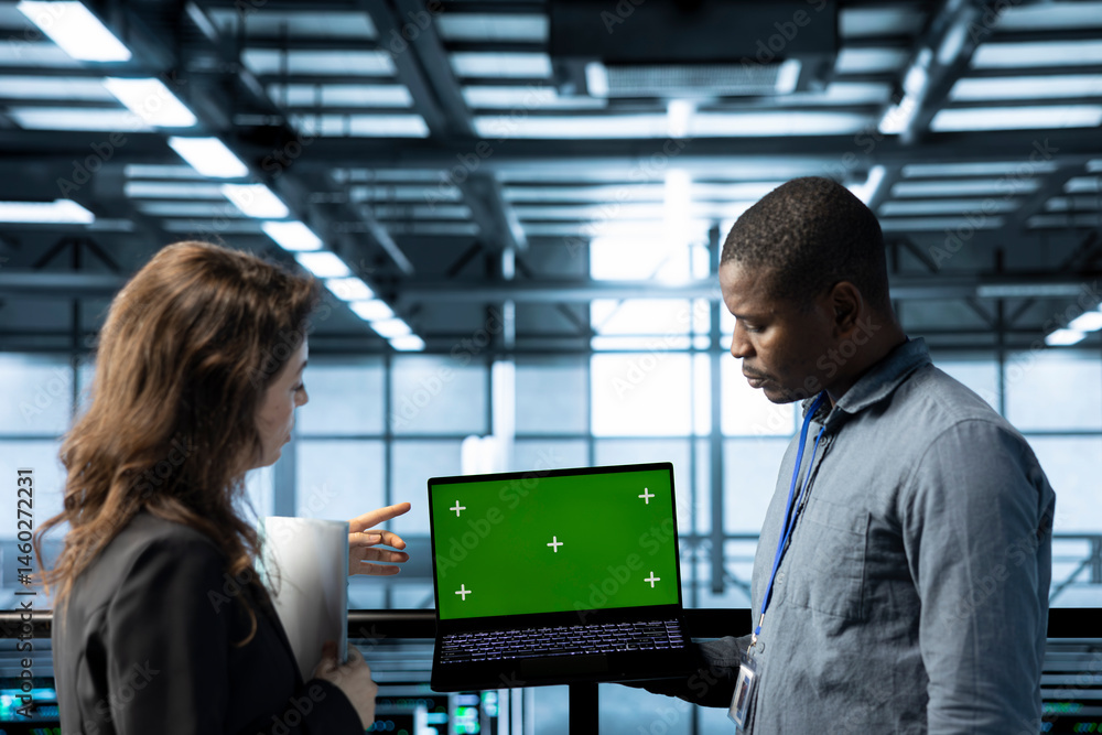 Poster employees in data center automating routine maintenance tasks with green screen laptop, executing di