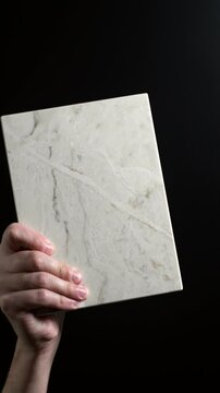 Luxury quartz stone texture pattern with trendy curly veins. Marble slab in hand on black background in Slow motion