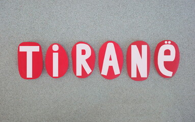 Tirane, albanian name of Tirana, capital city of Albania composed with red hand painted stone letters over green sand