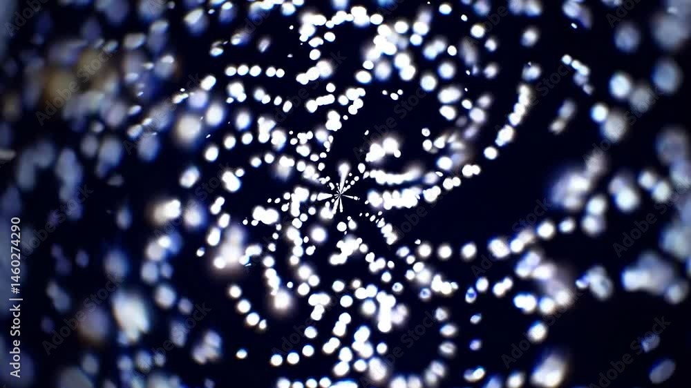 Poster white glowing particles are rotating on a dark background, creating a mesmerizing kaleidoscopic effe