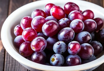 A bowl of grapes sitting on top of a wooden table.