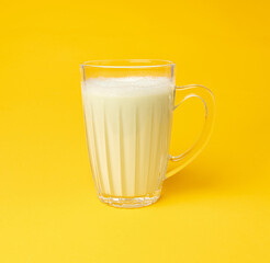 Vanilla milk shake in glass. Milkshake on yellow background, white whey protein smoothie