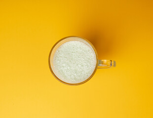 Vanilla milk shake in glass. Milkshake on yellow background, white whey protein smoothie