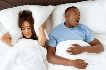 Family problems, apnea and insomnia due spouse. Young tired african american guy sleeping and...