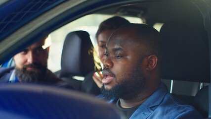 Happy customers shaking hands with car showroom salesman after finishing test drive and being satisfied. Clients reaching agreement with agent in dealership after driving vehicle, camera A