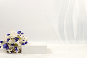 Abstract beautiful floral arrangement with white hyacinths and muscari, banner, elegant beauty concept. Empty product podium and fresh live spring flowers. Minimal modern aesthetics.