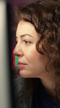 Vertical Video IT specialist at workstation programming on monitor and writing lines of code, using development tools and a terminal window interface. Woman debugging software before deadline. Camera