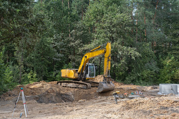 A yellow excavator is digging in the dirt
