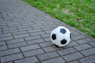 A white and black soccer ball is laying on a brick walkway