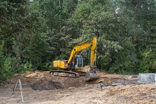 A yellow excavator is digging in the dirt