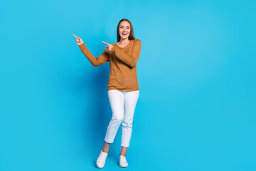 Lovely woman in casual outfit pointing in excitement against a bold blue background