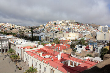 A panoramic view of Las Palmas de Gran Canaria's historic center from the Cathedral rooftop. The scene features colorful colonial buildings, cobblestone streets, and the charm of the city.