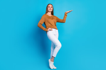 Lovely woman wearing casual sweater and white pants posing confidently against a bright blue background