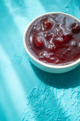 Spreading strawberry jam on toast bread on pink plate in close-up