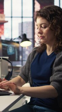 Vertical Video IT specialist at workstation programming on monitor and writing lines of code, using development tools and a terminal window interface. Woman debugging software before deadline. Camera