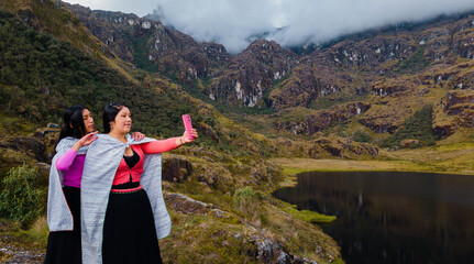 par de  Mujeres quechuas con vestimenta tradicional en América Latina, feliz mientras usa un teléfono inteligente mirada a un espacio publicidad y aislada en un fondo naturaleza,celular.Quechua.