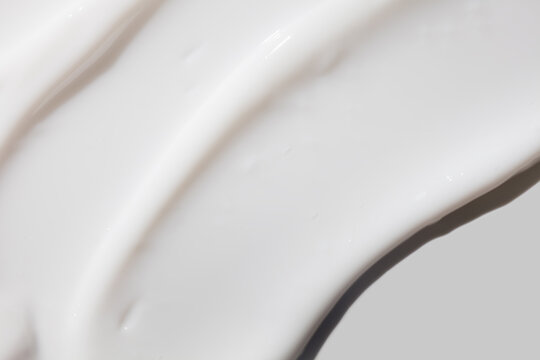 Cosmetic white cream balm or cleansing milk texture smudge isolated on gray background. Skin care beauty product sample swatch
