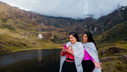 par de  Mujeres quechuas con vestimenta tradicional en América Latina, feliz mientras usa un teléfono inteligente mirada a un espacio publicidad y aislada en un fondo naturaleza,celular.Quechua.