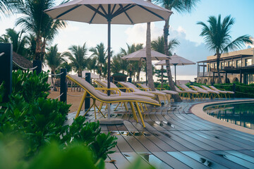 view of a set of long chairs with beige cushion on the side of a pool with open umbrellas