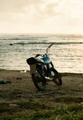 view of a two wheel motorbike parked in front of the ocean on a sunset