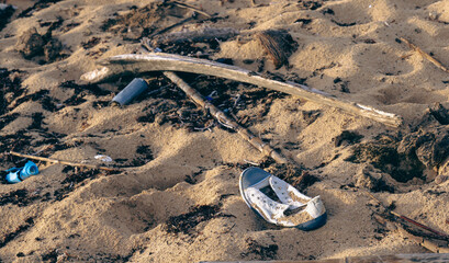 view of an abandoned white canva shoe on a sandy beach