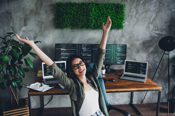 Young woman programmer celebrates success while working in a creative home office environment