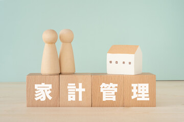 家計管理と書かれたブロック、人形、家の模型