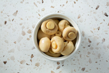 A top down view of a bowl of canned white mushrooms.