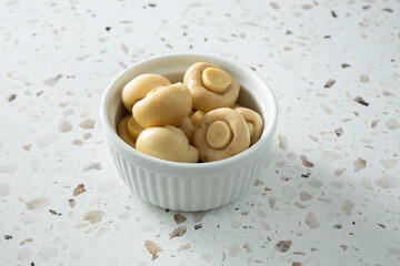A view of a bowl of canned white mushrooms.