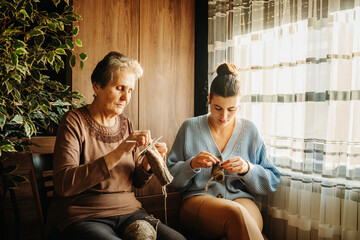Senior caucasian woman teach granddaughter how to knit with needles