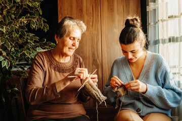 Senior caucasian woman teach granddaughter how to knit with needles