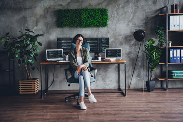 Young female programmer working remotely in a stylish home office with multiple screens and...