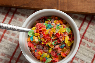 A top down view of a spoon scooping some popular rainbow flakes cereal.