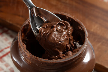 A closeup view of a spoon scooping some chocolate hazelnut spread out of a package container.