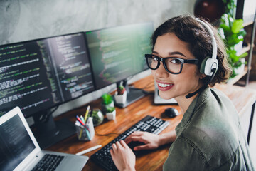 Young IT specialist coding in modern workspace wearing headset and glasses