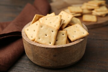 Tasty salty crackers on wooden table, closeup