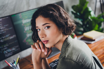 Professional young woman coder with curly hair working on programming project in comfortable indoor...