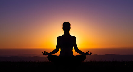 A silhouette of a person in lotus pose with sunrise light in the background