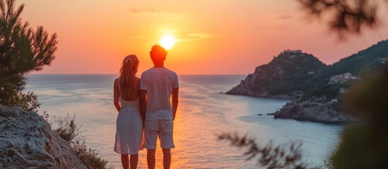 Fototapeta premium Couple Enjoying Sunset View From Cliff Over Ocean