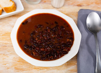 Mexican cooked black beans served in sauce on platter..